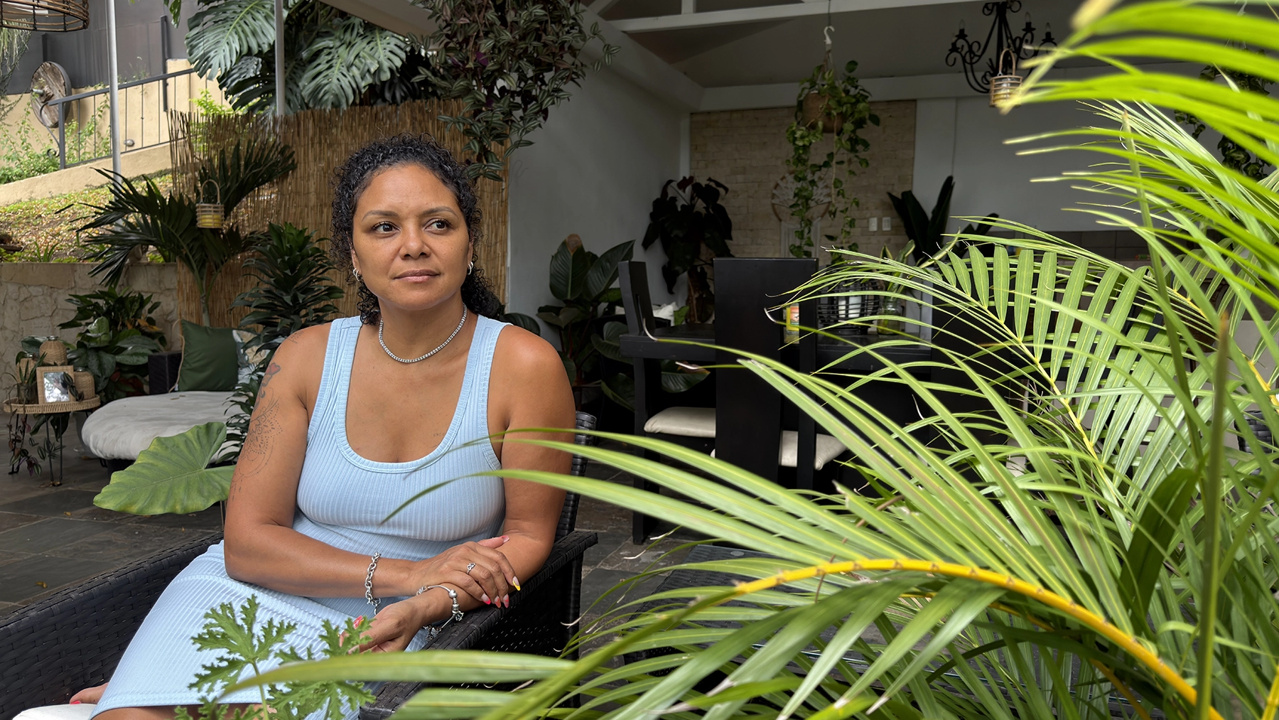 Quiet depletion in midlife — Nina Danilee sitting thoughtfully among plants in her Costa Rica home